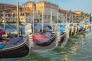 Gondolas in Grand Canal stake pier at golden sunset, Venice, Italy