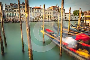 Gondolas in Grand Canal stake pier at golden sunset, Venice, Italy