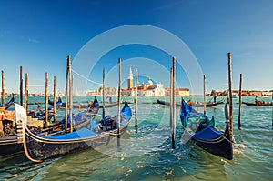 Gondolas moored docked on water in Venice. Gondoliers sailing San Marco basin waterway. San Giorgio Maggiore island