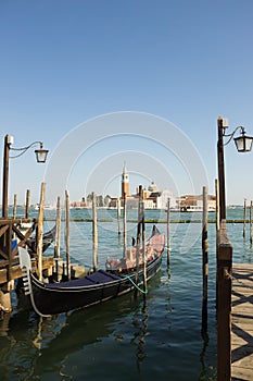 Gondolas moored on the pier of Saint Mark square, in the background is San Giorgio di Maggiore church, Venice, Italy