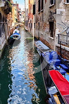 Gondolas and small boats on a narrow canal in Venice