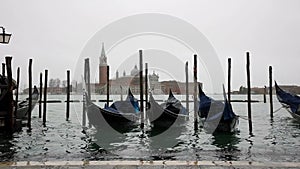 Gondolas in Venice Canal with San Giorgio Maggiore in the background in cloudy weather