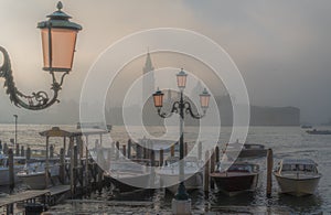 Gondolas in Venice at sunrise in morning fog. Veneto, Italy