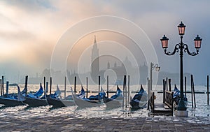 Gondolas in Venice at sunrise in morning fog. Veneto, Italy