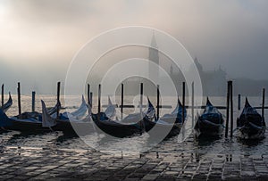 Gondolas in Venice at sunrise in morning fog. Veneto, Italy