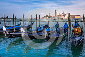 Gondole docked by wooden mooring poles in grand canal, Ethereal Venice, Italy