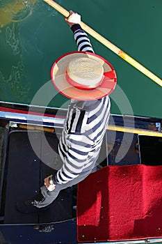 Gondolier with hat rowing a gondola in a Venetian canal in venice in Italy