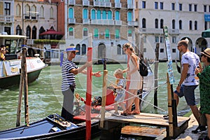 Gondolier invites passengers on board gondola in Venice
