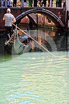 Gondolier navigating tourists in a Venice Canal