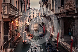 Gondolier rowing down a narrow canal in Venice, Italy