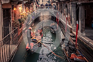 Gondolier rowing down a narrow canal in Venice, Italy