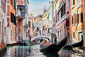 Gondolier rowing gondola on canal in Venice, Italy.