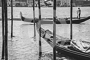 A gondolier or venetian boatman propelling a gondola on Grand Canal in Venice. Black and white photography