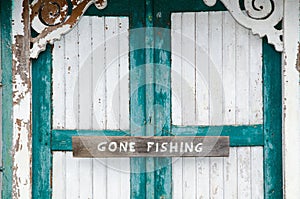 Gone fishing sign at weathered doors