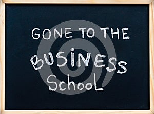 Gone to the business school message written with white chalk on wooden frame blackboard