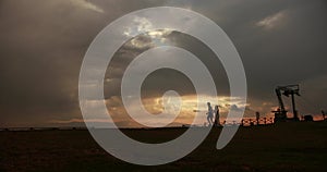 Gone with the wind. Picture of a lovely couple running along the road on the hill with beautiful red and grey sunset