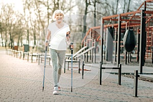 Good-appealing energetic lady cheerfully enjoying Nordic walking outdoor