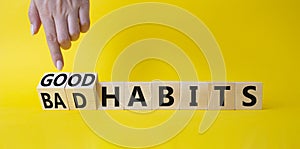 Good and bad Habits symbol. Businessman points at wooden cubes with words Bad Habits and Good Habits. Beautiful yellow background