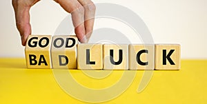 Good or bad luck symbol. Businessman turns wooden cubes and changes words `bad luck` to `good luck`. Beautiful yellow table, w