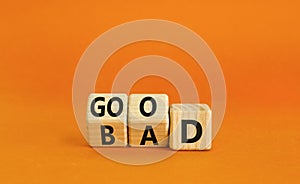 Good or bad symbol. Turned wooden cubes and changed the word bad to good. Beautiful orange table, orange background, copy space.