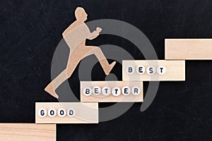 Good - Better - Best paper man climbing the steps to success in a conceptual image over black background