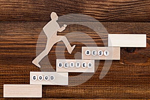 Good - Better - Best,  paper man climbing the steps to success in a conceptual image over wooden background