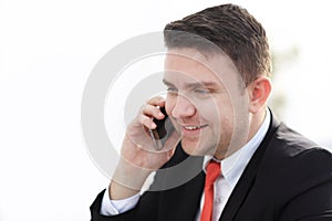 Good business talk. Handsome young man in formalwear talking on the phone and smiling while sitting