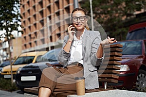 Good business talk. Happy beautiful business woman wearing eyeglasses talking on the phone and smiling while relaxing on