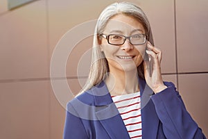 Good business talk. Portrait of a happy mature business woman wearing eyeglasses and classic wear talking on mobile