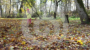 Good child girl fighting colorful autumn leaves with raker tool in backyard