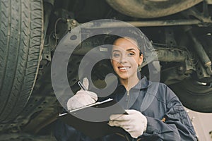 Good condition car undercarriage check concept, woman mechanic worker work checklist car garage