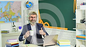 Good drink for good work. Bearded man with cup give thumb up. Senior teacher drink coffee in class. Hot caffeine drink