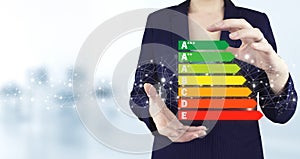 Good energy chart rating. Two hand holding virtual holographic energy efficiency icon with light blurred background. Concept of