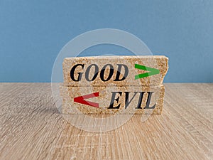 Good Evil symbol. Concept word Good and Evil on brick blocks. Beautiful wooden table, blue background. Sign Shows Difference