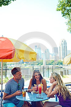 Good friends, good times. three young friends sitting at an outdoor cafe.