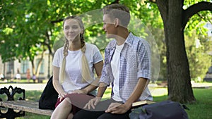 Good friends sitting on bench and talking, remembering past moments, funny story