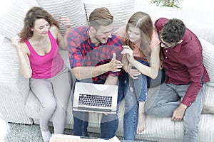 Good friends sitting on the couch and giving each other five.