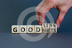 Good habits and life symbol. Businessman turns wooden cubes and changes words `good habits` to `good life`. Beautiful grey