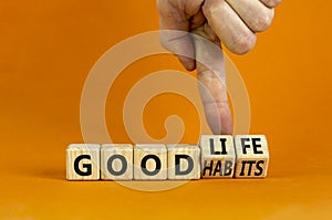 Good habits and life symbol. Businessman turns wooden cubes and changes words `good habits` to `good life`. Beautiful orange