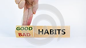 Good habits symbol. Businessman turns a wooden block and changes words `bad habits` to `good habits`. Beautiful white backgrou