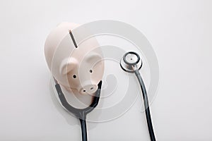 Good healthcare is expensive. High angle shot of a stethoscope around a piggybank in the studio.