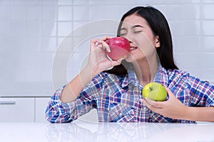 Good healthiness and healthy diet concept. Cheerful young woman holding and kiss fresh red apple covered her face in