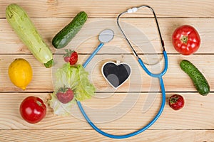 Good healthy and diet concept - Blackboard in shape of heart, stethoscope and vegetables, fruits and berries