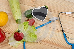 Good healthy and diet concept - Blackboard in shape of heart, stethoscope and vegetables, fruits and berries