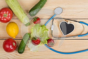 Good healthy and diet concept - Blackboard in shape of heart, stethoscope and vegetables, fruits and berries