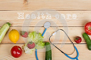 Good healthy and diet concept - text Health Care, stethoscope and vegetables, fruits and berries