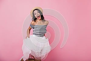 Good-humoured brunette girl playfully posing on pastel background. Studio shot of ecstatic young wo