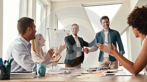 Good job Two cheerful colleagues shaking hands and smiling while having a meeting in the modern office