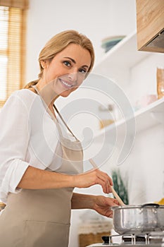 Good-lloking blonde woman cooking in the kitchen photo