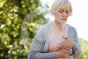 Good looking aged woman having heart attack outdoors